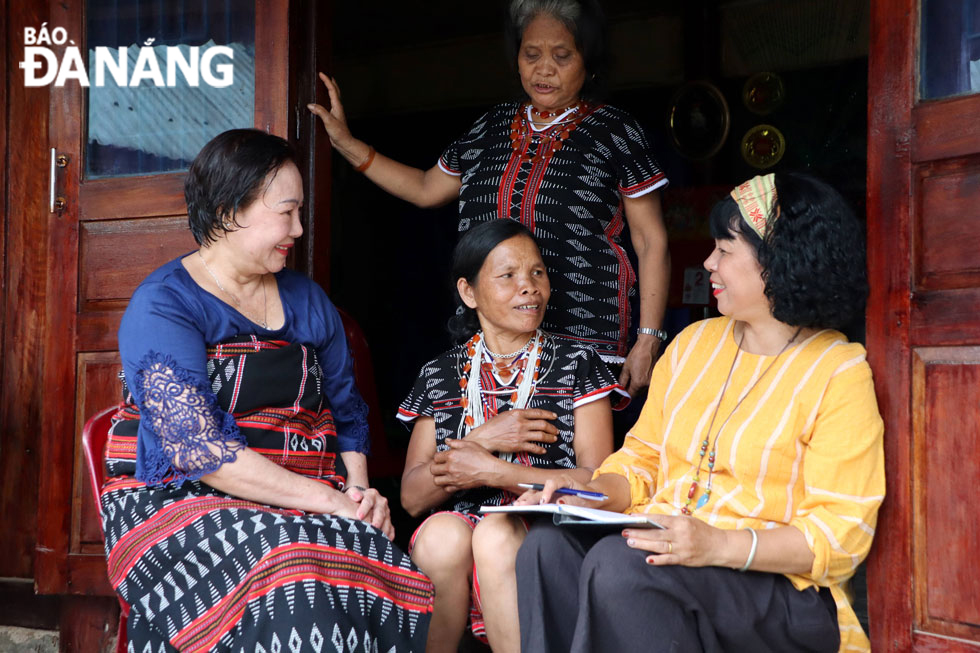 Visitors from Da Nang (left and right) learning about traditional clothes of Co Tu women