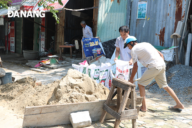 Người dân khẩn trương lấy cát chèn chống nhà cửa. Ảnh: VĂN HOÀNG