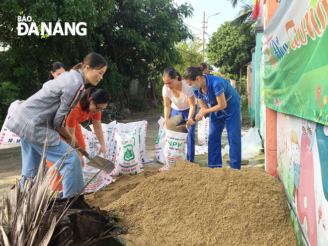 Giáo viên Trường mầm non Hướng Dương (quận Liên Chiểu) đổ cát vào bao để chằng chống mái tôn của trường.