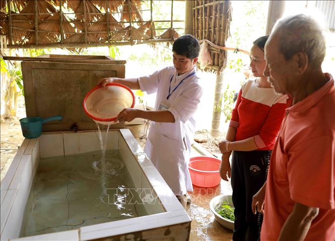 Nhân viên Trung tâm Y tế dự phòng huyện Lệ Thủy tiến hành khử khuẩn nước sinh hoạt bằng dung dịch Cloramin B cho hộ Nguyễn Ngọc Thái ở thôn Mai Thúy, xã Mai Thủy. Ảnh: Vũ Sinh - TTXVN