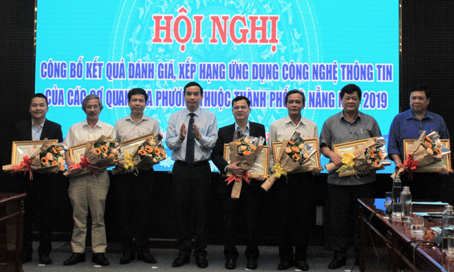 Phó Chủ tịch Thường trực UBND thành phố Lê Trung Chinh (thứ tư, từ trái qua) trao bằng khen cho các đơn vị dẫn đầu bảng xếp hạng kết quả ứng dụng công nghệ thông tin Đà Nẵng 2019. 			Ảnh: KHANG NINH