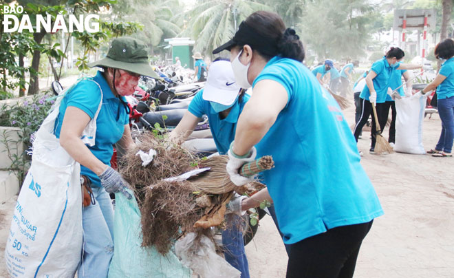 Phụ nữ quận Thanh Khê chung tay làm sạch môi trường tại tuyến đường Nguyễn Tất Thành.  Ảnh: THANH TÌNH	