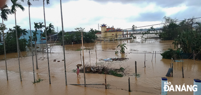 Water surging and spilling over a concrete road leading to a residential area in La Bong village, Hoa Tien Commune