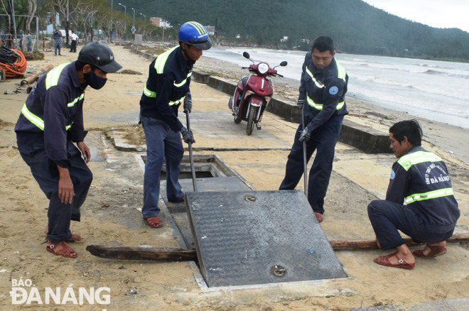 Workers of Da Nang Sewerage and Wastewater Treatment Company conducting maintenance on coastal outlets to prevent flooding.