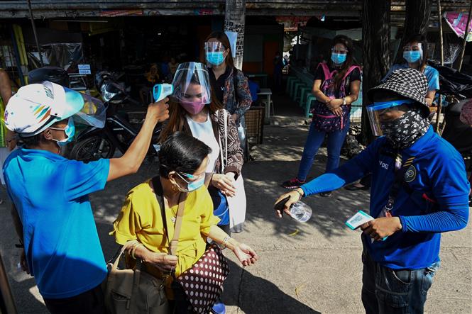 Đo thân nhiệt nhằm ngăn chặn sự lây lan của dịch COVID-19 trước khi lên xe buýt ở Manila, Philippines. Ảnh: AFP/TTXVN