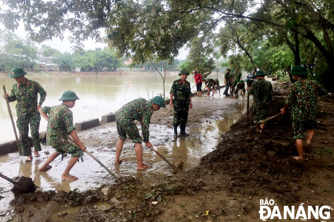 Lực lượng vũ trang thành phố tham gia khắc phục hậu quả bão, lũ trên địa bàn huyện Hòa Vang. Ảnh: Đ.N	