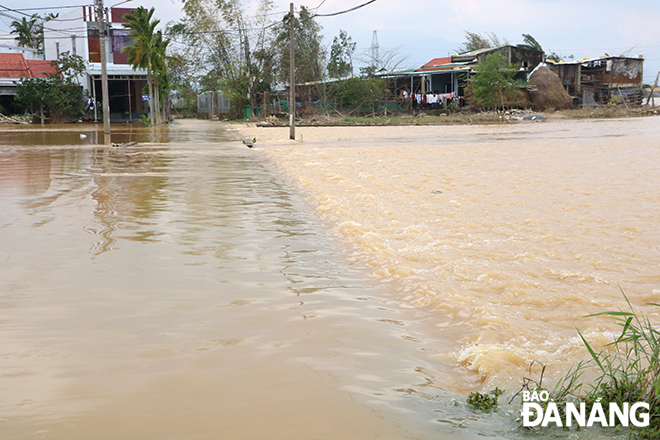 Con đường nối giữa các thôn bị nước tràn qua, chảy xiết, gây mất an toàn cho người dân khi đi lại. Ảnh: VĂN HOÀNG
