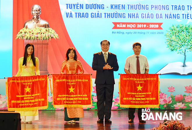 Authorised by the Prime Minister, municipal People’s Committee Chairman Huynh Duc Tho 2nd, right) awarding the national government-granted Emulation Flag to three groups