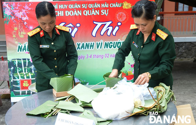 Đại úy Dương Thị Lan (bên phải) gói bánh chưng tặng người nghèo dịp Tết Nguyên đán.  Ảnh: CÁT TƯỜNG	