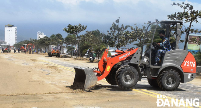 Các đơn vị quân đội huy động phương tiện làm vệ sinh trên tuyến đường Hoàng Sa - Võ Nguyên Giáp - Trường Sa sau bão số 13. 	         Ảnh: LAN ANH