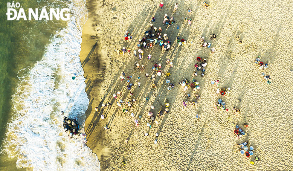 A beach is bustling with many fishermen, seafood traders, and buyers at an early-morning fish market