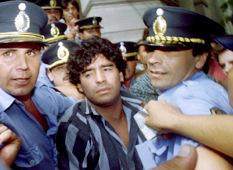 Cảnh sát hộ tống Maradona khỏi tòa án tháng 3-1994 liên quan đến cáo buộc ông bắn các nhà báo bên ngoài nhà riêng ở thành phố Mercedes. Ảnh: Reuters