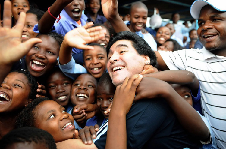Các học sinh hân hoan khi Maradona đến thăm một trường học ở Nam Phi tháng 1-2010. Ở thời điểm này ông giữ vai trò huấn luyện viên đội tuyển Argentina. Ảnh: Getty Images