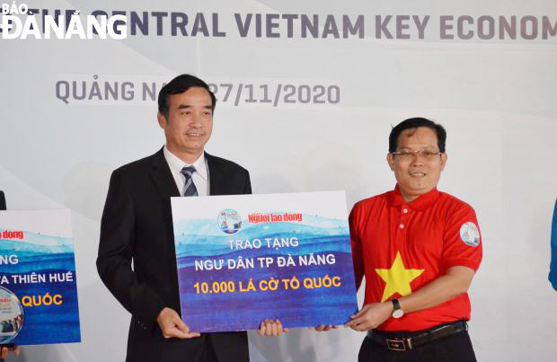 On behalf of the Da Nang authorities and people, municipal People's Committee Standing Vice Chairman Le Trung Chinh (left) receiving 10,000 national flags presented by the ‘Nguoi Lao Dong’ (Labourer) Newspaper for the soon distribution to local fishermen