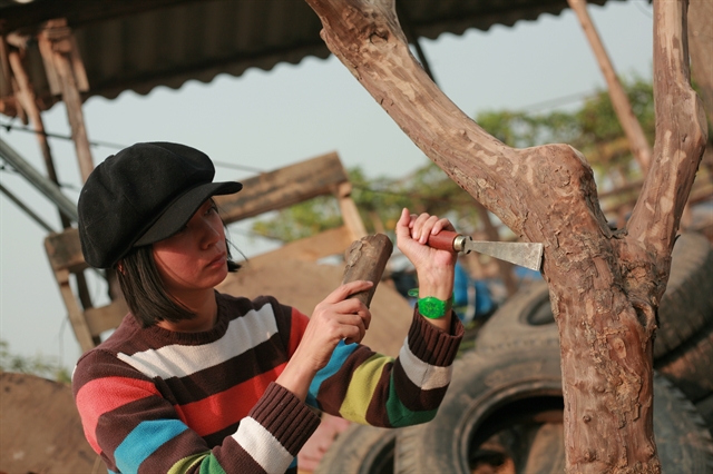 Đức chisels a tree trunk to create playground equipment. The social enterprise she co-founded, Think Playgrounds, has built more than 180 free playgrounds for children across Việt Nam. Photo courtesy of Chu Kim Đức