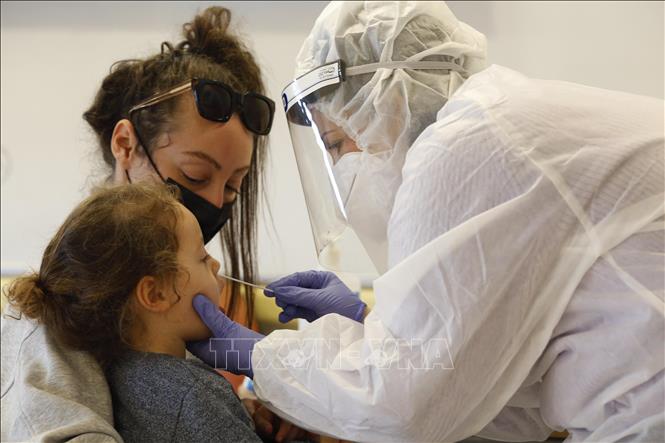 Nhân viên y tế lấy mẫu dịch xét nghiệm COVID-19 cho trẻ em tại Rishon Letzion, Israel ngày 8/12. Ảnh: THX/TTXVN