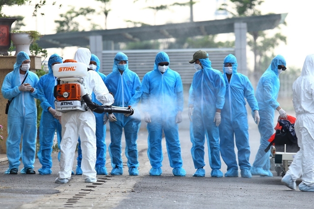 Health workers at National Hospital for Tropical Diseases in Hà Nội spray disinfectants on a group of Vietnamese workers returning to Việt Nam from Equatorial Guinea on a rescue flight with 120 suspected Covid-19 cases on board in July 29.