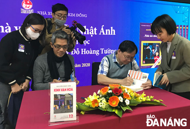 Nhà văn Nguyễn Nhật Ánh (người ngồi, phải) và họa sĩ Đỗ Hoàng Tường ký tặng bạn đọc trong sự kiện kỷ niệm 25 năm Kính vạn hoa ra tập đầu tiên.  Ảnh: HOÀNG THU PHỐ