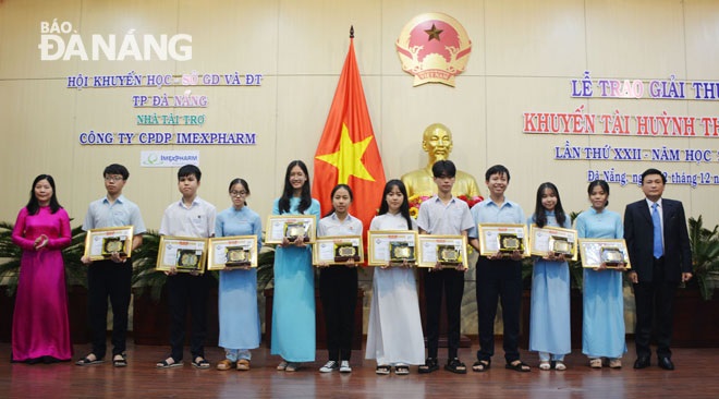 Director of the municipal Department of Education and Training Le Thi Bich Thuan (first left) and Da Nang Fatherland Front Committee Vice Chairman Tran Viet Dung (first right) presenting cash gifts and Certificates of Merit to some honourees