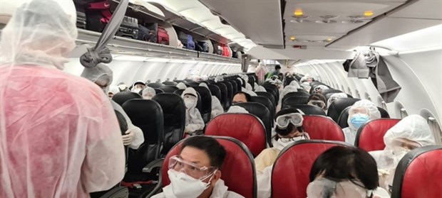 Vietnamese citizens wearing masks and protective suits during a repatriation flight from Indonesia conducted by Vietjet on November 30. (Photo: VNA)