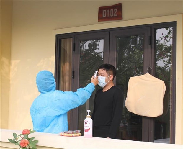 Measuring body temperature of a man at a concentrated quarantine facility (Source: VNA)