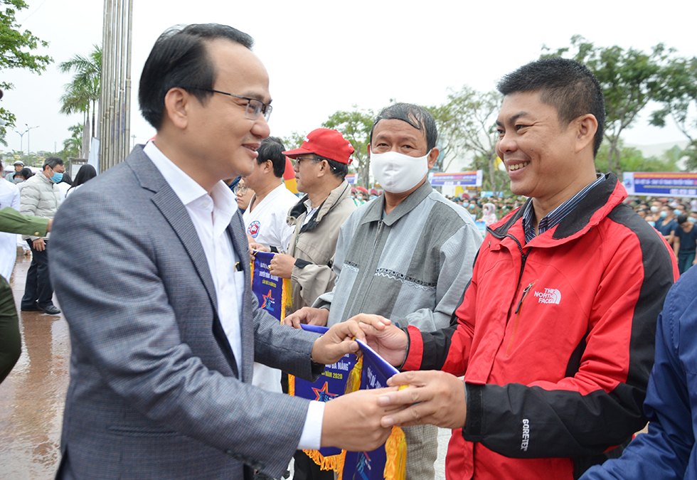 Head of the Da Nang Department of Publicity and Training Nguyen Dinh Vinh giving souvenir flag to representatives from the groups of participating runners