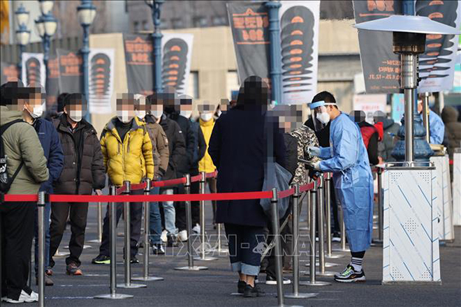 Nhân viên y tế lấy mẫu xét nghiệm Covid-19 cho người dân tại trung tâm xét nghiệm tạm thời ở ngoại ô Seoul, Hàn Quốc ngày 26-12. Ảnh: YONHAP/TTXVN