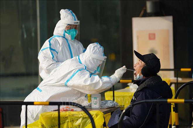 Nhân viên y tế lấy mẫu xét nghiệm Covid-19 cho người dân tại Bắc Kinh, Trung Quốc ngày 26-12. Ảnh THX/TTXVN