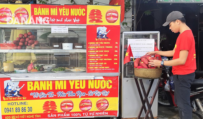 Tủ “bánh mỳ miễn phí” được trang trí lá cờ đỏ sao vàng. Người bán mặc áo in hình quốc kỳ Việt Nam để lan tỏa tinh thần yêu nước, cổ vũ ý chí tự lực, tự cường vượt qua khó khăn. Ảnh: L.P