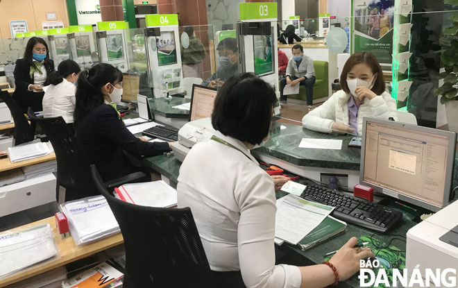 Commercial banks is reducing their lending rates in December so that businesses can access more preferential loans. Transaction activities are seen at the Da Nang branch of Vietcombank in this illustration.