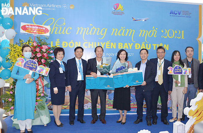 Đại diện lãnh đạo Sở Du lịch thành phố, hãng hàng không Quốc gia Việt Nam tặng quà cho hai vị khách may mắn trên chuyến bay đầu năm mới. Ảnh: THU HÀ