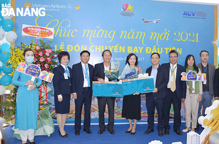 Representatives of the municipal Department of Tourism (4th from right), and Vietnam Airlines presenting gifts to two lucky business-class passengers on New Year’s first flight