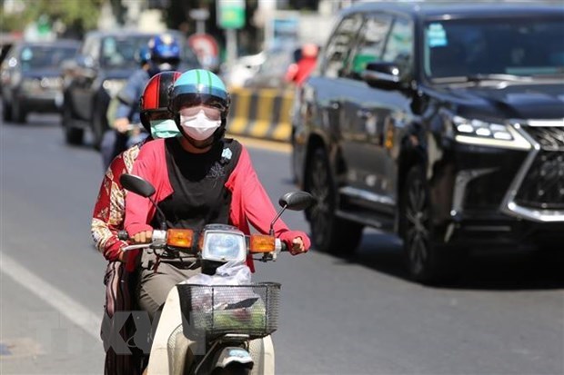 People wear face masks while moving on a road in Phnom Penh capital of Cambodia (Photo: VNA)