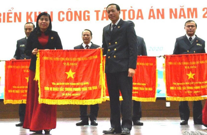 Bà Nguyễn Thị Cảnh, Chánh án TAND thành phố Đà Nẵng (bên trái, hàng đầu) nhận cờ “Đơn vị xuất sắc trong phong trào thi đua năm 2020” của Chính phủ tại Hội nghị triển khai nhiệm vụ năm 2021. Ảnh: PV	