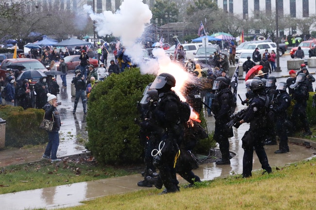 Cảnh sát bị người biểu tình quang nghị viện bang Oregon ném pháo hoa vào. Ảnh: Salem Reporter
