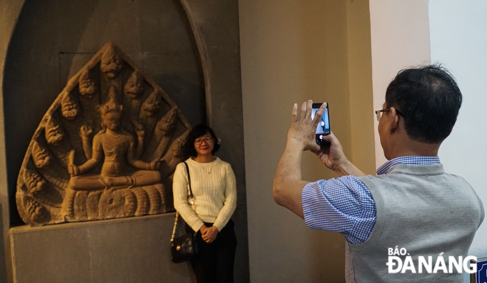 A tourist taking souvenir photos with artifacts on display at Da Nang Museum of Cham Sculpture