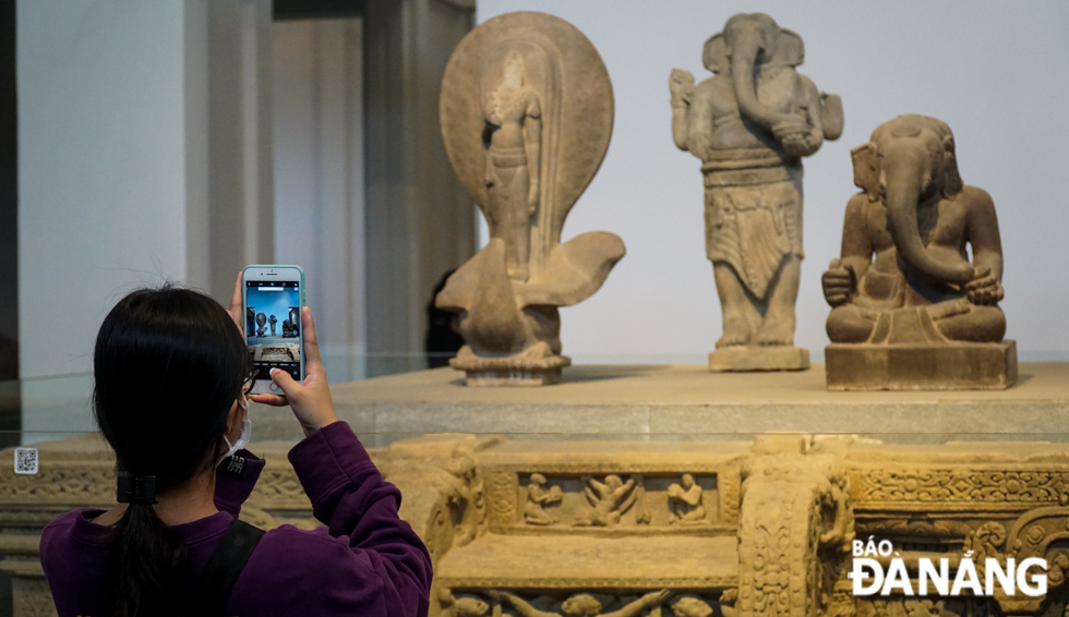 A young person saving photos of the statute of Ganesha and the My Son E1 Pedestal, both Viet Nam's national treasures, on display at the Da Nang Museum of Cham Sculpture