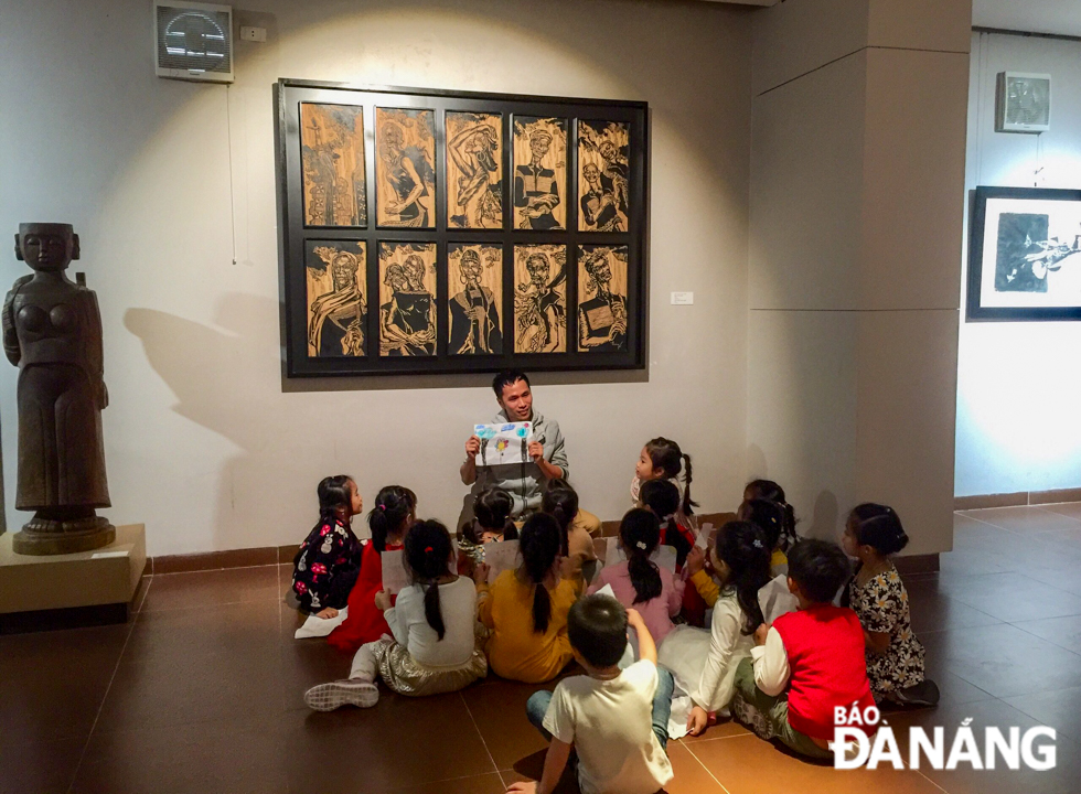 A museum staff introducing the Vanh Khuyen Preschool pupils to traditional folk paintings