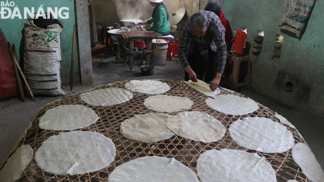 Cơ sở sản xuất bánh tráng Túy Loan của Bà Đặng Thị Túy Phong hoạt động từ 2 giờ sáng. Trong ảnh: Bà Phong đang đặt bánh vừa tráng xong lên lồng tre để hơ than. Ảnh: V.HOÀNG