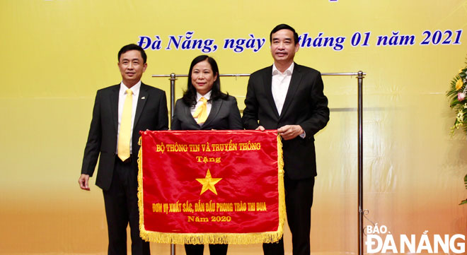 Chủ tịch UBND thành phố Lê Trung Chinh  (bìa phải) trao Cờ thi đua năm 2020 của Bộ Thông tin và Truyền thông tặng Bưu điện thành phố. Ảnh: PHONG LAN	