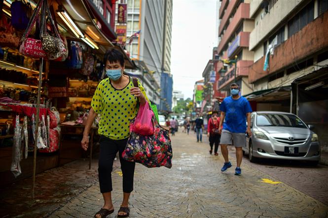 Người dân Malaysia đeo khẩu trang, giãn cách xã hội. Ảnh: AFP/TTXVN
