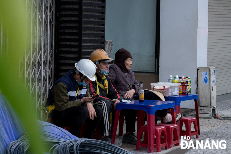 Workers stooping in the chilly wind at a pavement café during their lunch break