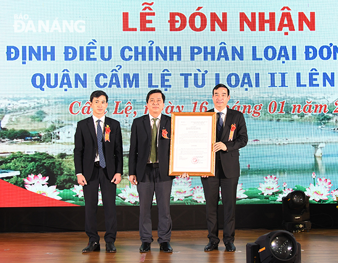 Da Nang Party Committee Deputy Secretary cum People's Committee Chairman Le Trung Chinh (right) handing over the Decision made by the Ministry of Home Affairs regarding the recognition of Cam Le District as a first-class administrative unit