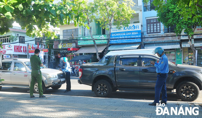 Thanh tra giao thông kiểm tra việc dừng, đỗ ô-tô sai quy định trên tuyến đường Phan Đăng Lưu. Ảnh: PHƯƠNG UYÊN