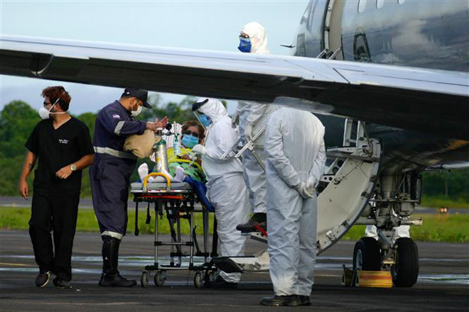 Nhân viên y tế chuyển bệnh nhân mắc Covid-19 lên máy bay tại Manaus, Brazil ngày 16-1-2021. Ảnh: THX/TTXVN