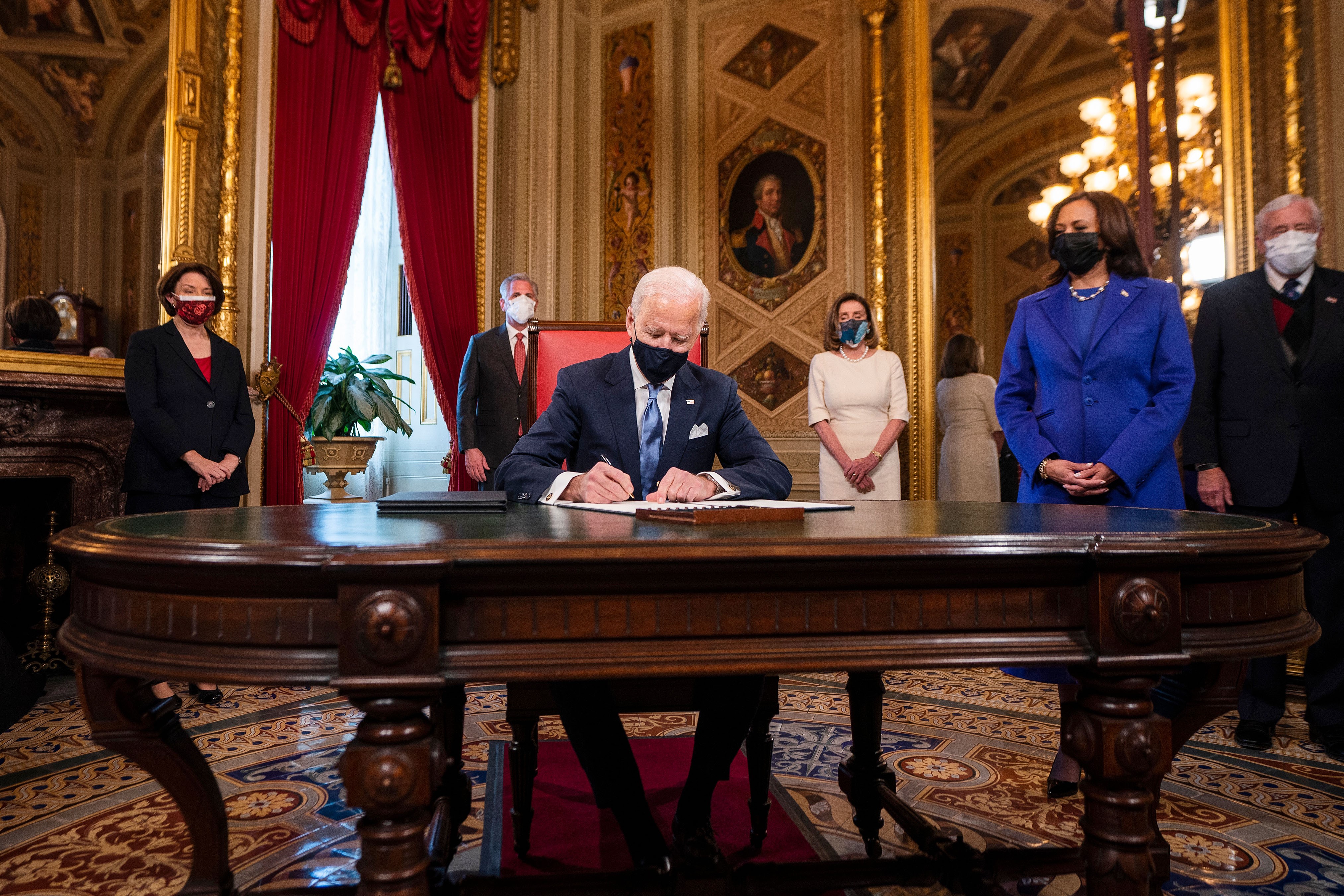 Tổng thống Mỹ Joe Biden ký 3 sắc lệnh tại phòng Bầu dục trong ngày đầu tiên nhậm chức 20-1-2021, đứng cạnh ông là Phó Tổng thống Kamala Harris (phải). Ảnh: Reuters	