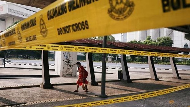 A woman wearing a protective mask walks on a street in Kuala Lumpur (Photo: Reuters)