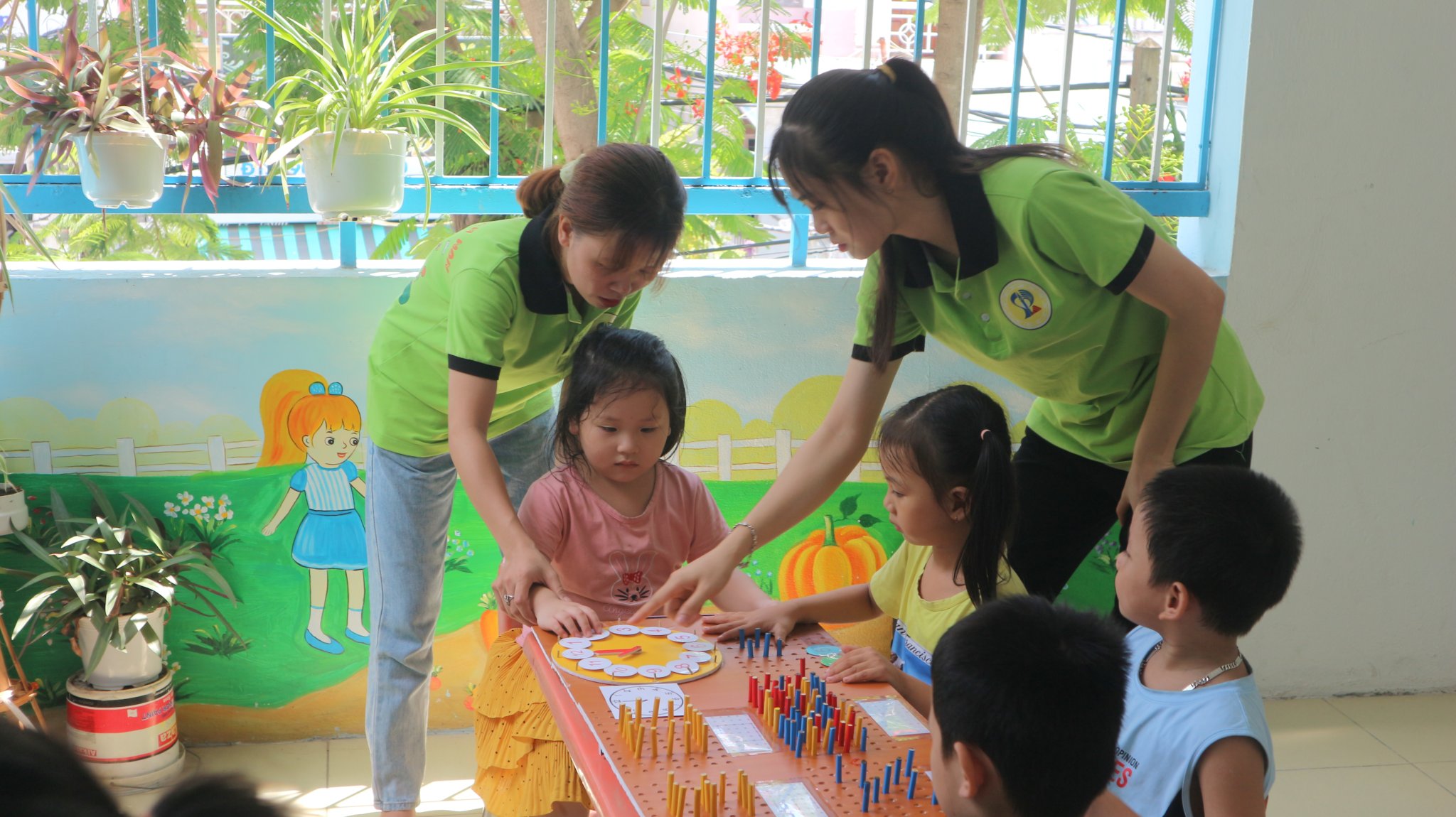 A group of students from the municipal University of Education instructing some Hoa Mi preschoolers to use their Math toys and tools 