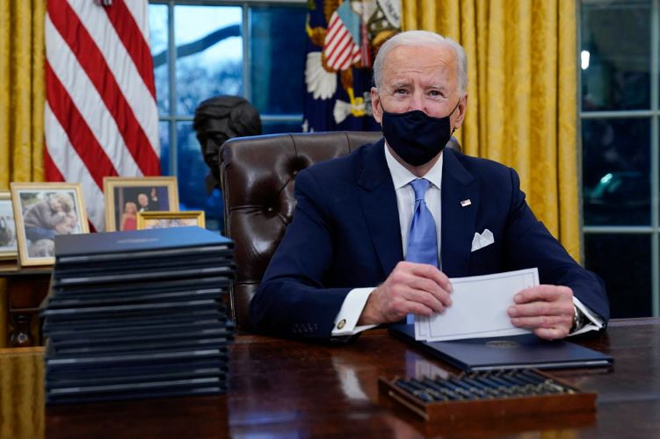 Tổng thống Joe Biden ký sắc lệnh điều hành đầu tiên tại phòng Bầu dục của Nhà Trắng vào ngày 20-1. Ảnh: AP