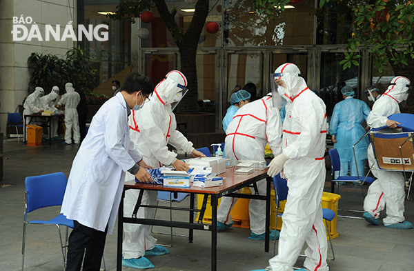 Medical staffers wearing medical protective suits preparing to take nose and throat swab samples from the reporters for the testing